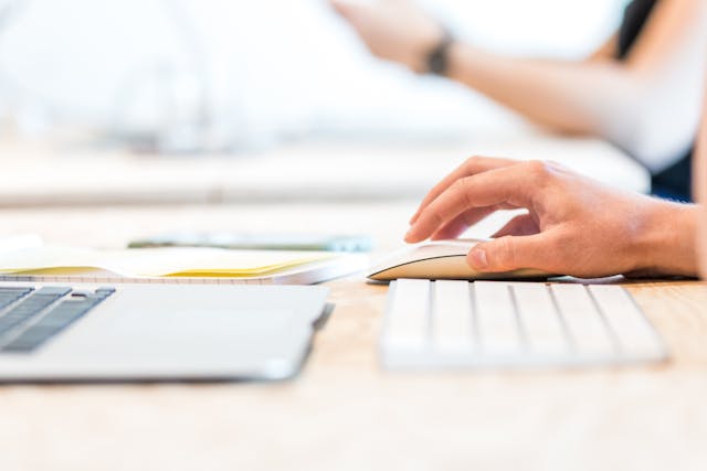 a hand on a computer mouse working at a desk