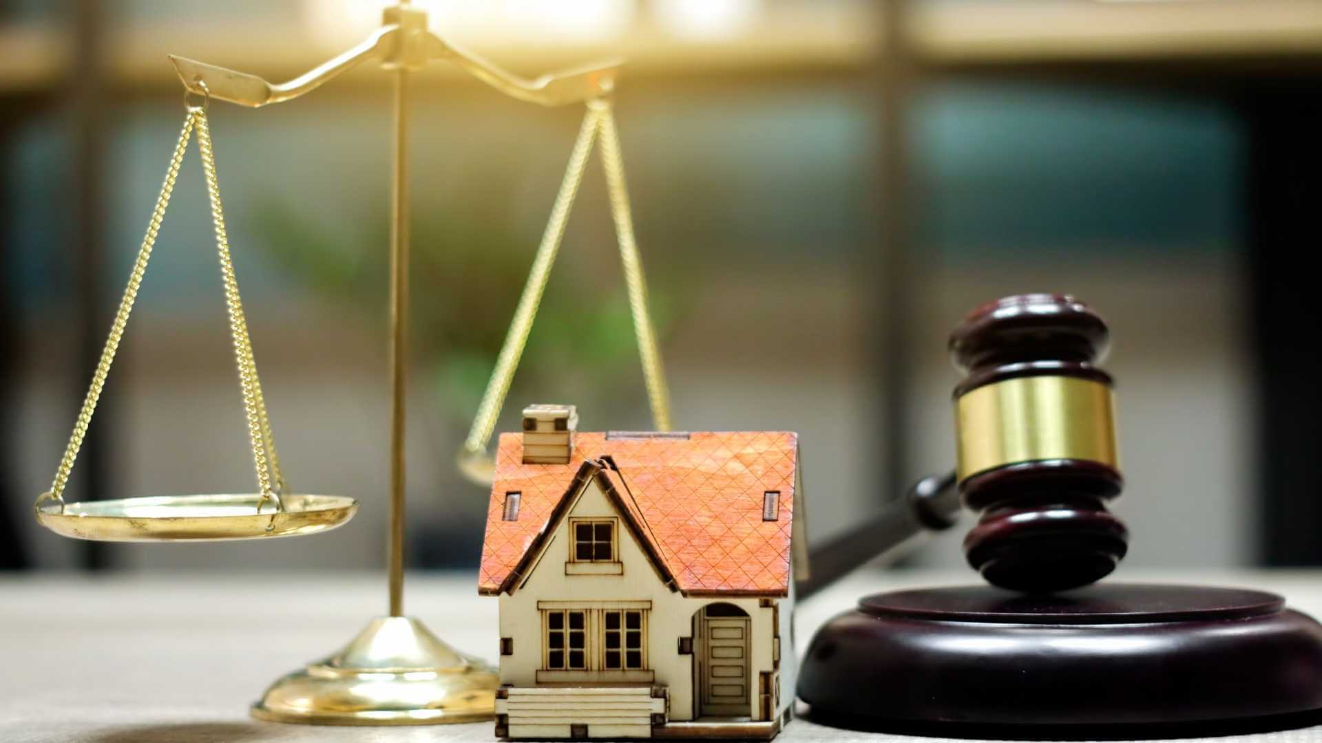 a legal balance, home figurine and a judges gavel on a table