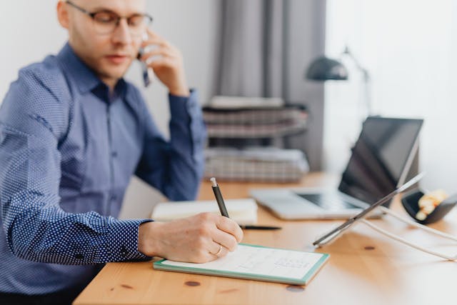 person sitting at their desk writing something in a notebook